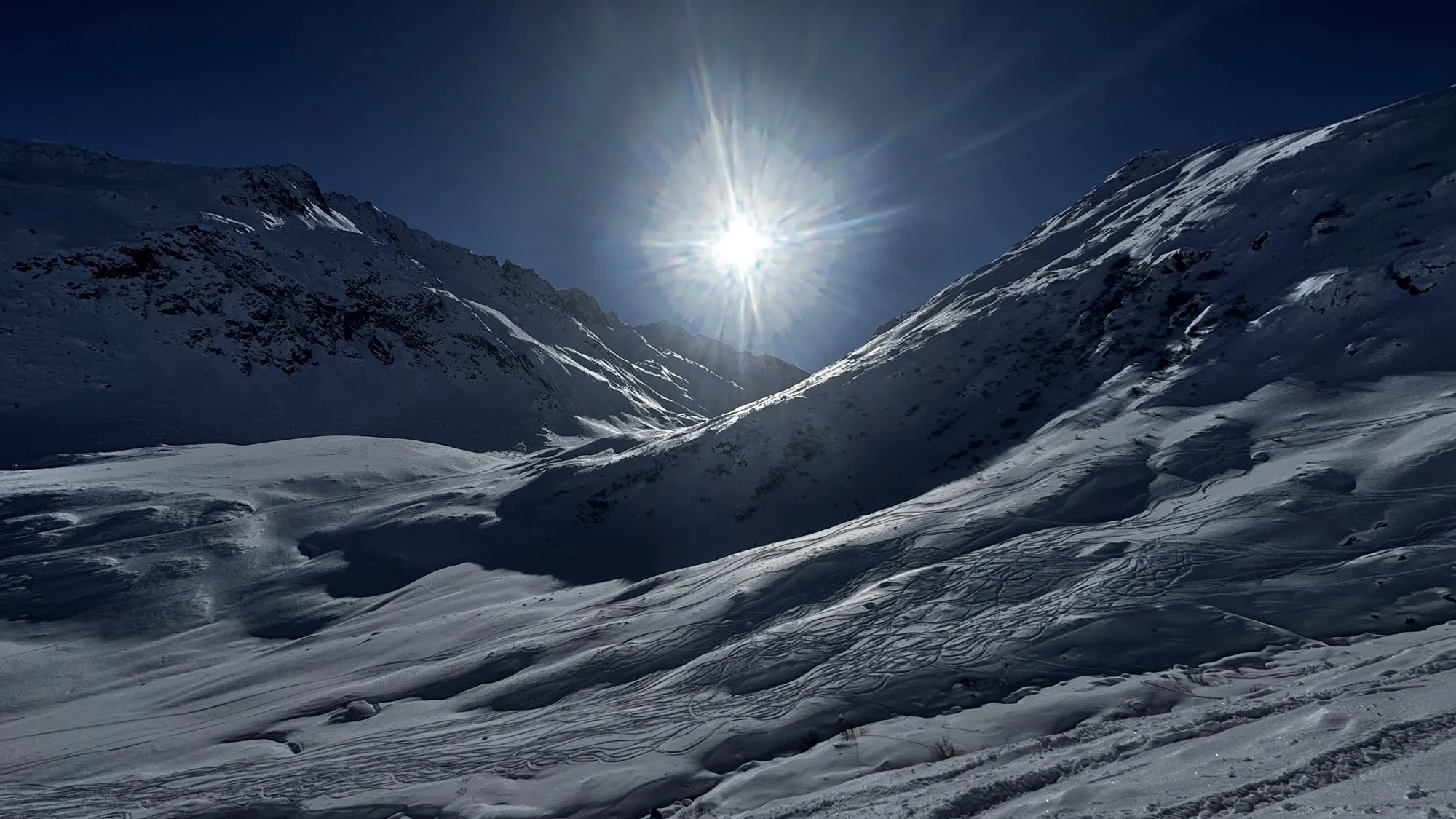 The sun shining between two snowy ridges